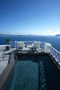 a swimming pool with chairs and the ocean in the background at Armeni Village in Oia
