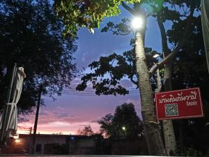 een straatlicht met een bord naast een boom bij Wapipathum Earthen House in Ban Na Lao