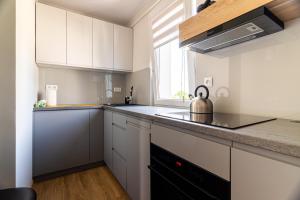 a kitchen with white cabinets and a tea kettle on the counter at Victus Apartamenty, Apartament Antonina in Sopot