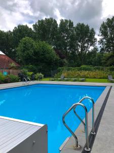 a blue swimming pool with a metal hand rail at Hotel Molengroet in Noord-Scharwoude