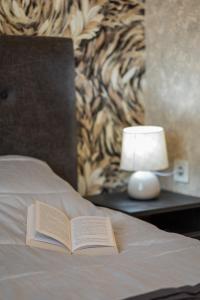 un libro en una cama con una lámpara en una mesa en ashlife_home, en Liepāja