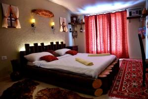 Schlafzimmer mit einem großen Bett mit weißer Bettwäsche und roten Vorhängen in der Unterkunft HANI I VJETER Boutique Hotel in Prizren