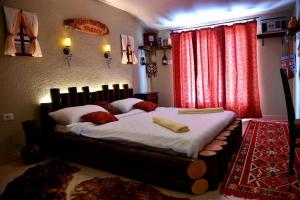 um quarto com uma cama grande com lençóis brancos e cortinas vermelhas em HANI I VJETER Boutique Hotel em Prizren