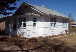 ein kleines weißes Haus mit schwarzem Dach in der Unterkunft Holiday Cottage in Canora