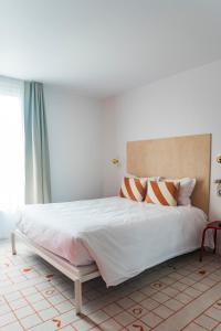 een slaapkamer met een groot wit bed met oranje en witte kussens bij Hôtel Ô Rouge Gevrey-Chambertin - Teritoria in Gevrey-Chambertin