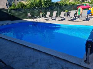 a swimming pool with blue water and chairs at Medziotoju kiemelis in Palanga
