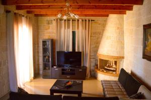 sala de estar con sofá, TV y chimenea en Villa Alexandra, en Stavros