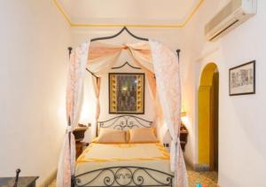 Riad Maison Arabo-Andalouse في مراكش: غرفة نوم بسرير مع مظلة