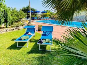 zwei Liegestühle und Sonnenschirme neben einem Swimmingpool in der Unterkunft Mastro Vanni - Urban Masseria in Ragusa