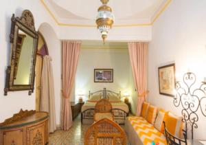 Riad Maison Arabo-Andalouse في مراكش: غرفة نوم بسرير واريكة