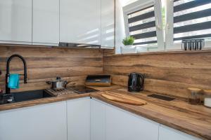a kitchen with white cabinets and a wooden wall at Apartament u Mirki in Puck