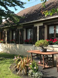 einem Picknicktisch vor einem Haus mit Blumen in der Unterkunft Chambre tout confort du Tilleul in Bosc-Bénard-Commin