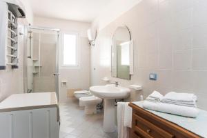 Baño blanco con lavabo y aseo en Piccola casa Marina, en Villa San Pietro