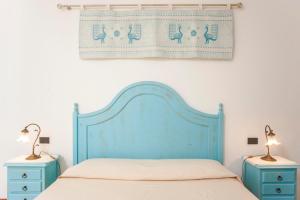 1 cama con cabecero azul y 2 mesitas de noche en Piccola casa Marina, en Villa San Pietro