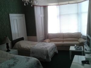 - une chambre avec un canapé, un lit et une fenêtre dans l'établissement Capital Guest House, à Édimbourg