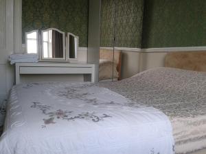 - une chambre avec un lit, une commode et un miroir dans l'établissement Capital Guest House, à Édimbourg