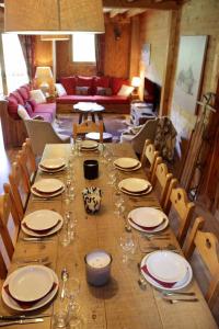 een lange houten tafel met borden en glazen erop bij Chalet Le Bouton D'or in Les Deux Alpes