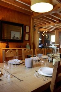 a wooden table with plates and wine glasses on it at Chalet Le Bouton D'or in Les Deux Alpes