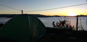 a green tent with the sunset in the background at Amantani Lodge in Amantani