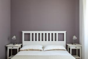 a bedroom with a white bed and two nightstanduments at Apartments Silvija in Mokošica