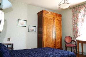 a bedroom with a bed and a wooden cabinet at Chambres du Manoir de Blanche Roche in Saint-Jouan-des-Guérets