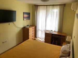 a bedroom with a bed and a desk and a television at Cosy Apartment with beautiful terrace in the heart of Varna in Varna City