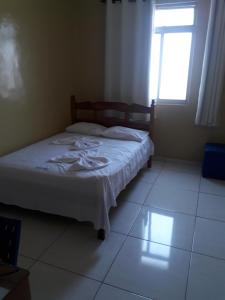 a bedroom with a bed and a window and a white floor at Hotel Brasil in Feira de Santana