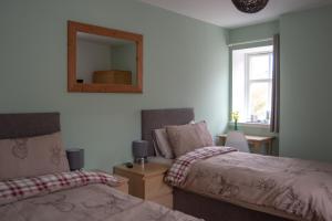 a bedroom with two beds and a mirror and a window at Altquhur Byre in Drymen