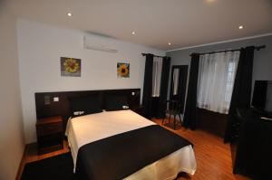 a bedroom with a black and white bed and a television at Casa da Abrótea in Lajes do Pico +30 photos