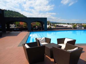 a large swimming pool with chairs and a table at Santa Tecla Palace in Acireale