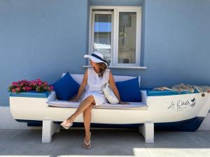 a woman in a white dress and hat sitting on a boat at b&b le onde praiola in Terrasini