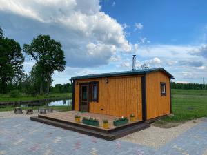 a small wooden cabin with a deck in a field at Brīvdienu māja Kaļviļumi 