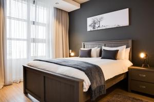 1 dormitorio con 1 cama grande y 2 ventanas en Matrix Apartments en Ciudad del Cabo