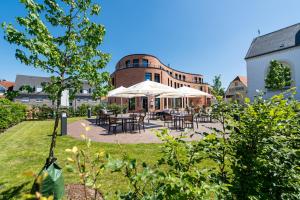 un patio con mesas y sombrillas frente a un edificio en Hotel Leib & Seele en Drensteinfurt