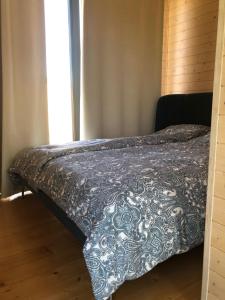 Una cama en un dormitorio con una manta. en Liepa SaulesKempings, en Mērsrags