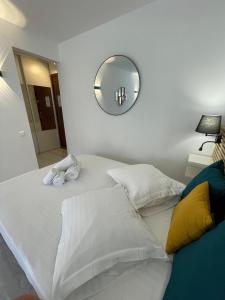 een groot wit bed met een spiegel aan de muur bij Chaleureux studio, 200m de la plage, parking, wifi in Roquebrune-Cap-Martin