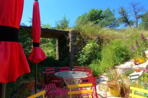 a patio with a table and chairs and an umbrella at La Ferme De Chenevier, La Roulotte Fleurie 2/4pers in Saint-Victor