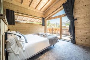 a bedroom with a bed and a large window at Madame Vacances Chalet Alpinium 1 in Les Boisses