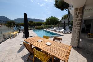 eine Terrasse mit einem Holztisch und Stühlen sowie einem Pool in der Unterkunft Villa Talabar in Cassis