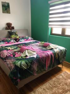 a bed with a colorful comforter in a bedroom at Apartmani NINA Zlatar in Nova Varoš