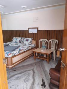 a bedroom with a bed and two chairs and a table at Hotel Rajpal Guest House in Dehradun