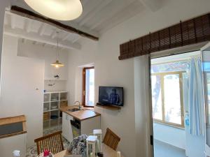 a kitchen with a table and a tv on the wall at Porticciolo in Marina di Campo