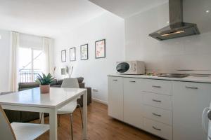 eine Küche und ein Esszimmer mit einem Tisch und einer weißen Küche in der Unterkunft Apartamentos Casa Yoli en Maro in Maro