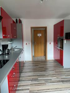 a kitchen with red cabinets and a wooden door at Ferien- und Monteurwohnungen Andrej in Eisenach +4 photos
