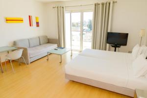 a white living room with a couch and a tv at Marina Club Lagos Resort in Lagos