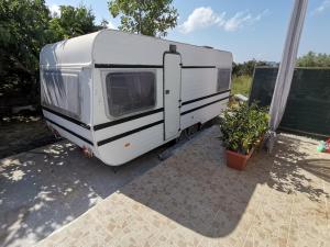 a white trailer is parked next to a plant at Green Garden Caravan in Zakynthos