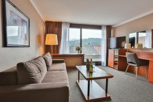 Hotel Quellenhof في بادن بادن: غرفة معيشة مع أريكة وطاولة
