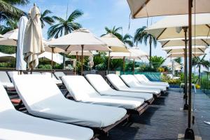 a row of white lounge chairs with umbrellas and a pool at Beachbreak Holiday Letting in Durban