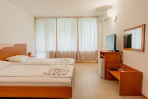 een slaapkamer met 2 bedden en een flatscreen-tv bij Хотел Ескана in Shkorpilovtsi