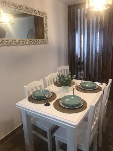 een witte tafel met witte stoelen en borden en een spiegel bij Casa D'Aldeia in Aldeia da Mata